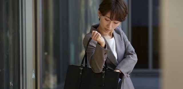 オフィス街で腕時計を確認するビジネスウーマン