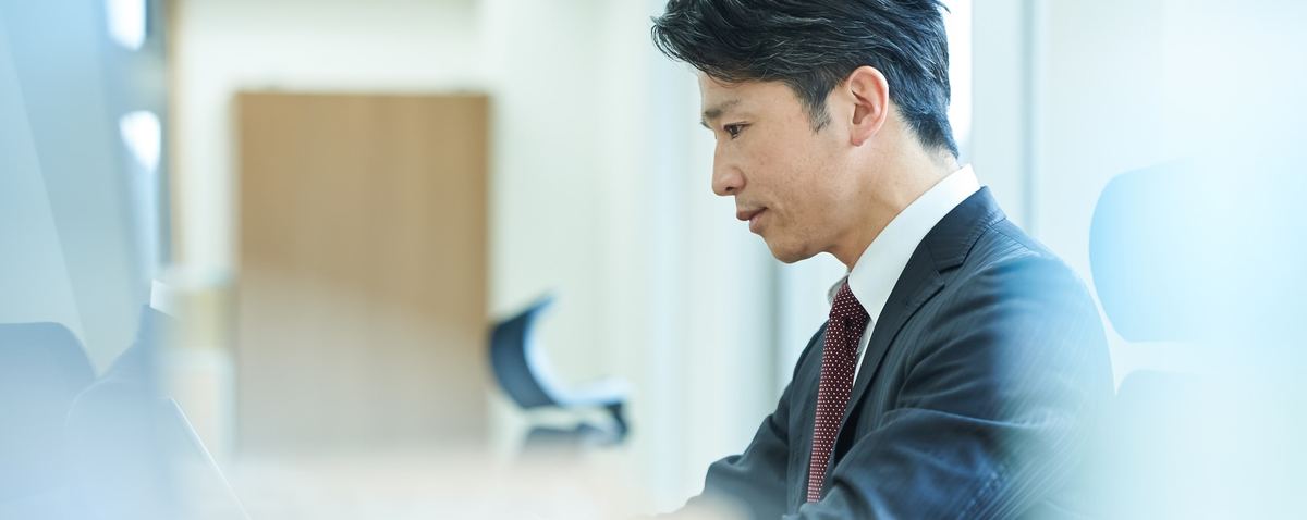 思案顔で考え込むスーツ姿の経営者