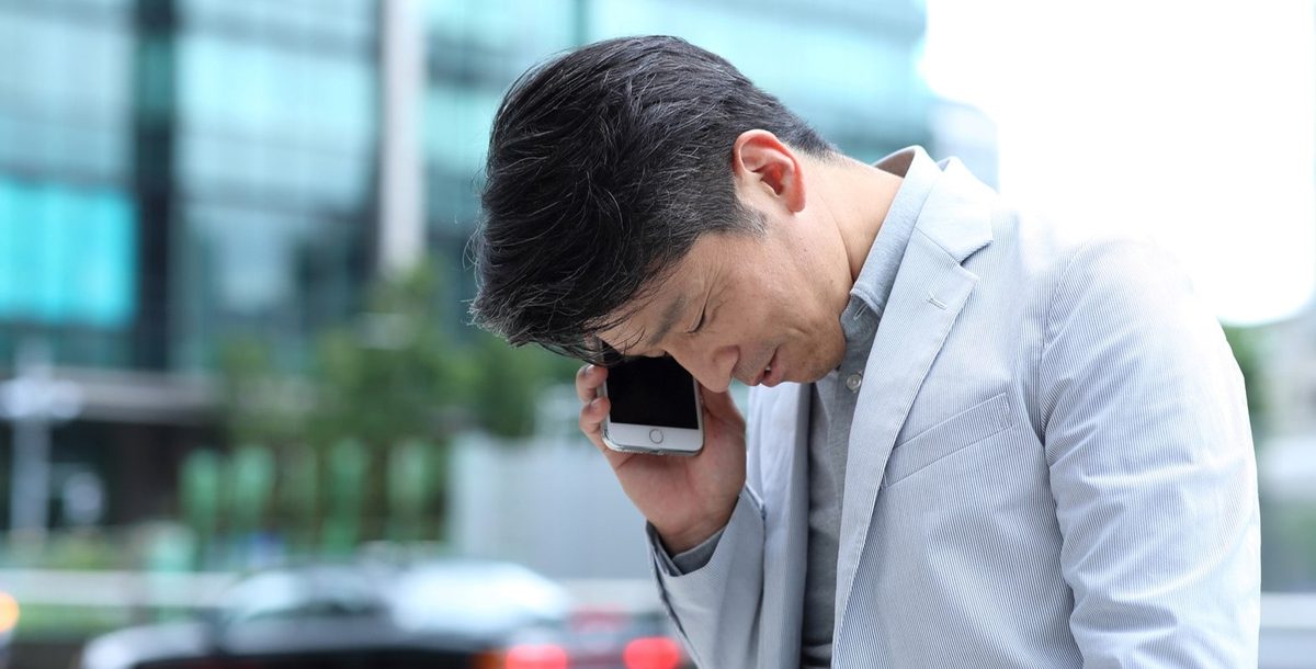 電話をしながら困った表情を見せるビジネスパーソン