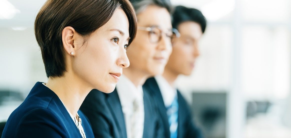 真剣な表情で横並びに座るビジネスパーソン3人